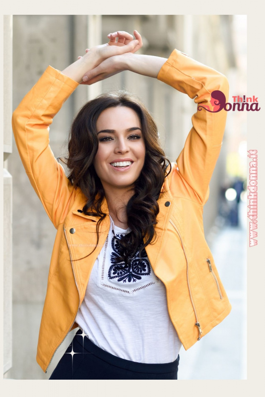 bella donna sorridente capelli lunghi castani giubbotto biker colorato giallo