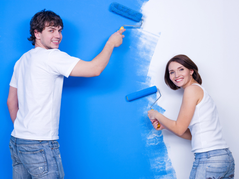 giovane bella coppia uomo donna pitturano muro colore azzurro