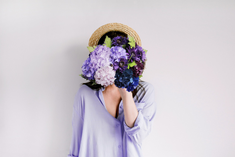 donna si copre il viso con fiori viola lilla ortensie foglie 