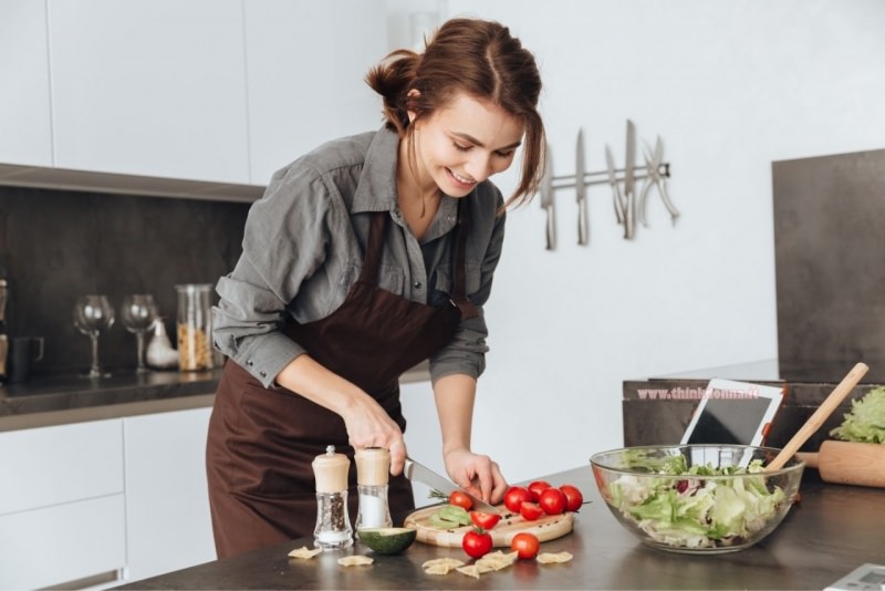 giovane donna impara a cucinare taglia pomodoro coltello tagliere hobby passatempo restare a casa