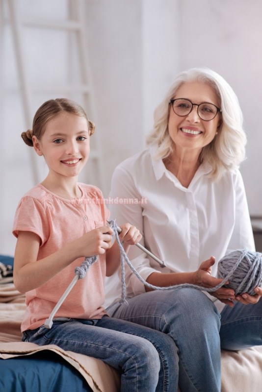 bambina sorriso impara a lavorare a maglia ferri insegnante nonna restare a casa hobby passatempo