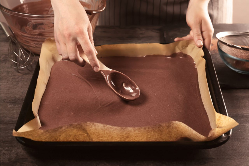 preparazione pan di spagna biscotto rotolo cacao carta forno teglia mani di donna frusta