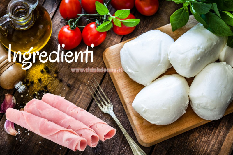 mozzarella su tagliere di legno ampolla olio rotoli prosciutto cotto pomodorini forchetta tavola foglie basilico