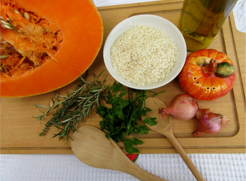 tagliere cucchiaio legno ciotola riso zucca arancione semi rosmarino prezzemolo cipolla