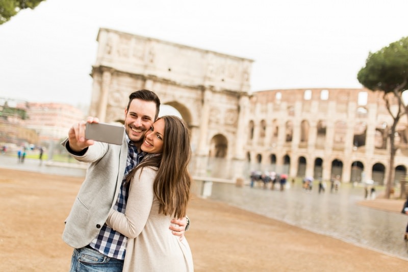 innamorati fanno selfie uomo donna coppia sorriso davanti colosseo roma