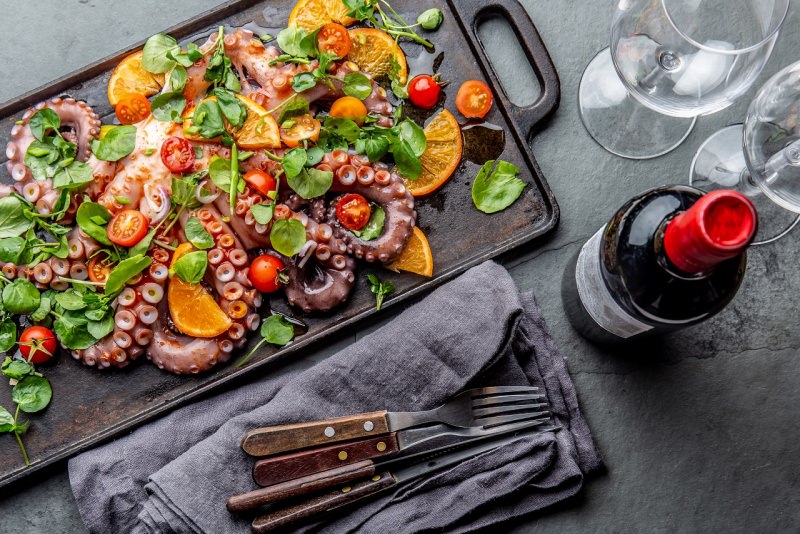 insalata di polpo con arance pomodorini e crescione bottiglia calici bicchieri vino rosso