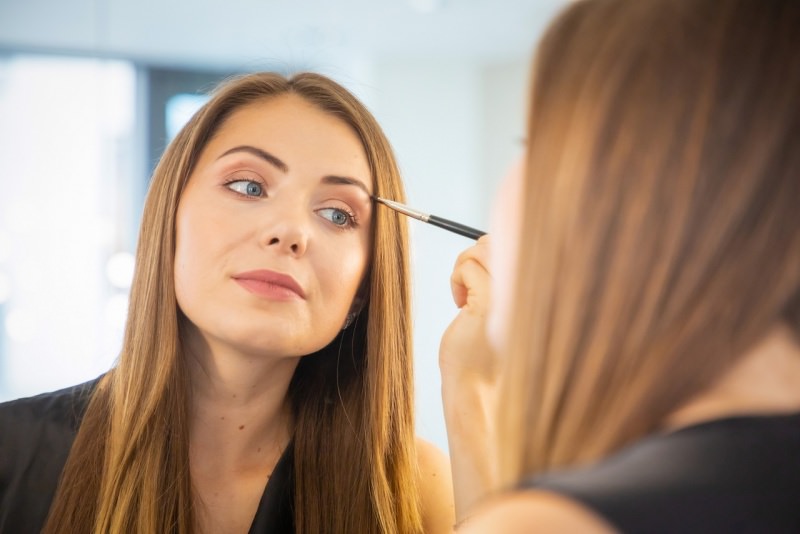 bella donna si mette il trucco make-up allo specchio pennello makeup occhi azzurri