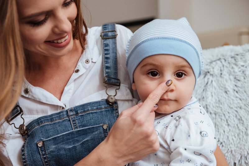 raffreddore bambino piccolo in braccio mamma che gli tocca nasino