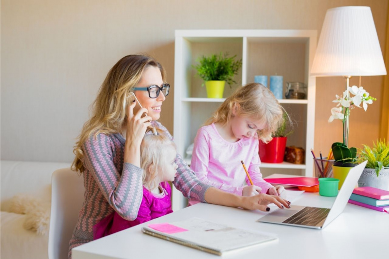 mamma sorridente parla al telefono figlia piccola in braccio bambina scrive lavoro e compiti a casa