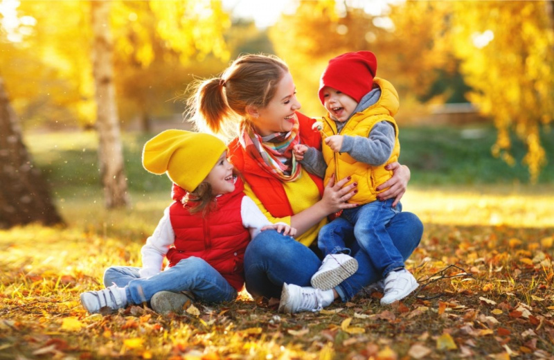 famiglia felice gioca all'aperto gilet per neonato giacca smanicata foglie gialle autunnali jeans