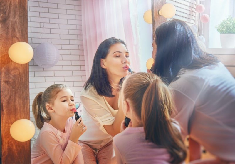 mamma e figlia si truccano mettono rossetto allo specchio