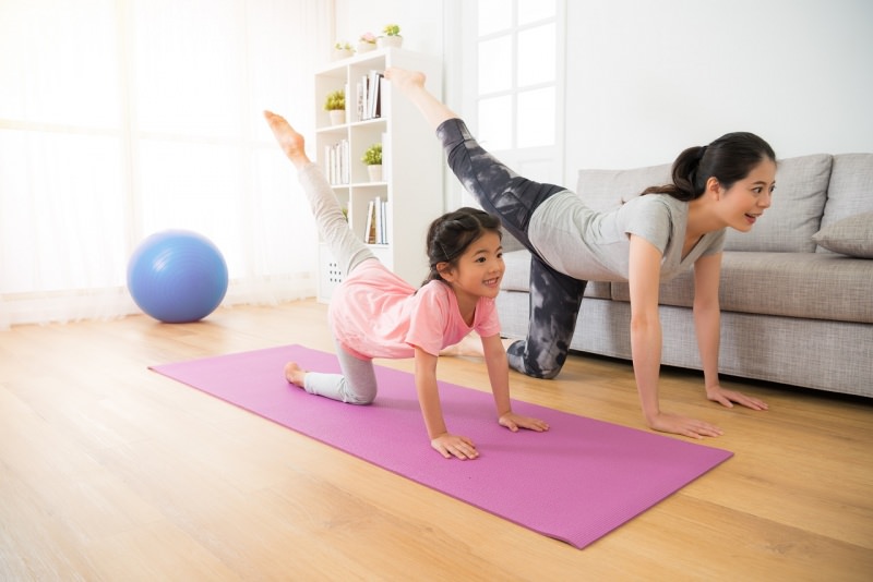 mamma e figlia fanno fitness esercizi fisici in casa tappeto divano