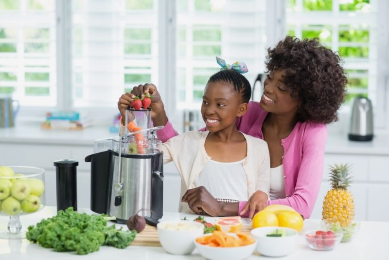 mamma e figlia preparano frullato smoothie estrattore frutta verdure