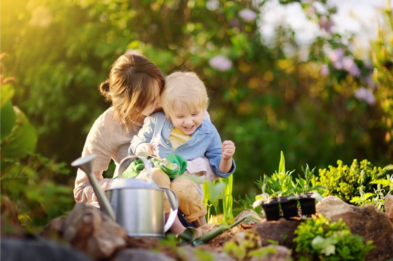 mamma donna e figlio bambino coltivano orto annaffiatoio earth day giornata della terra