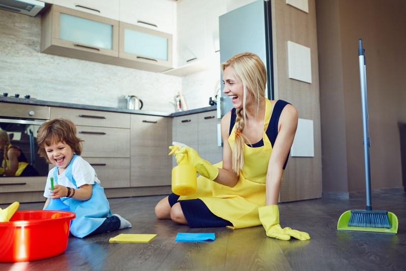 mamma e figlio si divertono facendo pulizie pavimento secchio spugna