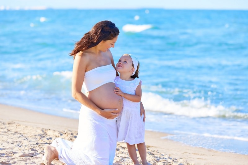 mamma incinta con figlia sulla sabbia spiaggia mare estate