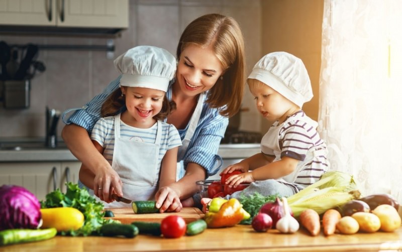 mamma prepara verdure con figlia e figlio cappello chef sorrisi cucina