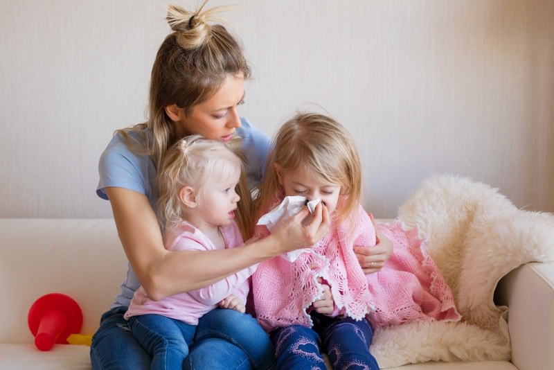 mamma si prende cura della figlia bambina raffreddore soffia naso bimba piccola guarda medicine