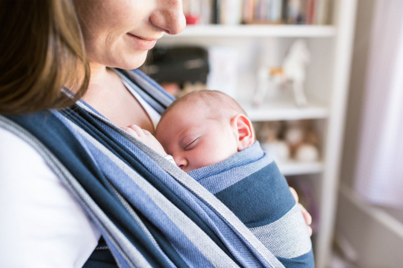 neonato dorme tranquillo fascia in braccia della mamma donna sorridente