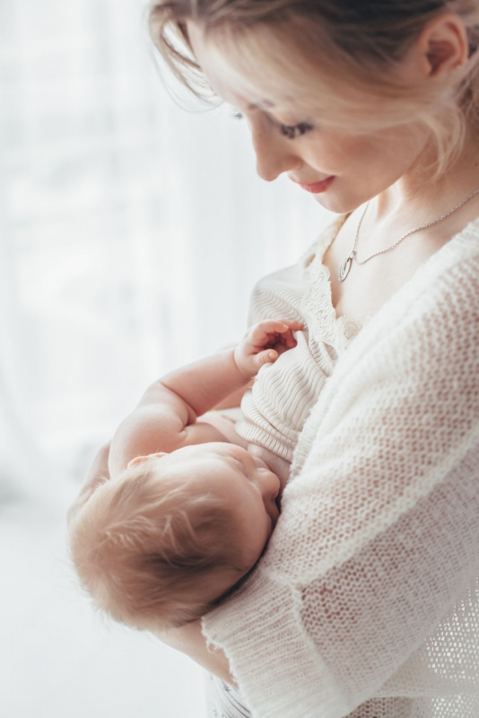 donna capelli biondi guarda figlio che tiene in braccio durante allattamento al seno