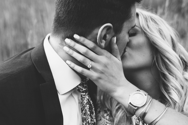 uomo e donna si baciano appassionatamente anello di fidanzamento diamante al dito mano di lei foto bianco e nero