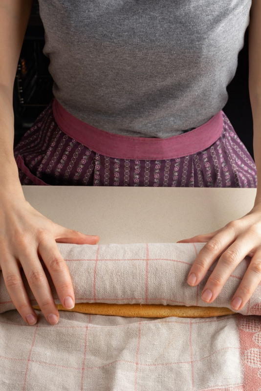 preparazione rotolo pan di spagna arrotolato e avvolto carta forno canovaccio cotone