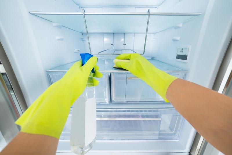 mani con guanti di gomma gialli spruzzino pulizia frigorifero