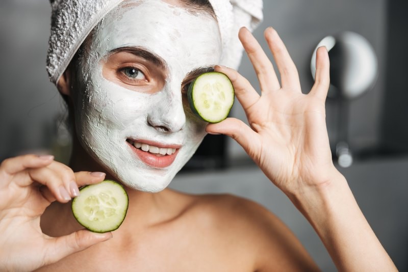 viso donna con turbante spugna maschera di bellezza sul viso occhi azzurri fette i cetriolo