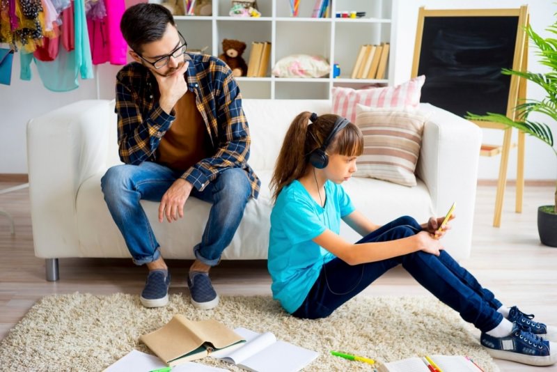 padre e figlia adolescente smartphone cuffie genitori figli