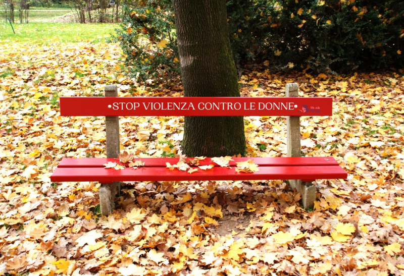 stop violenza contro le donne scritta bianca su panchina rossa foglie autunno alberi