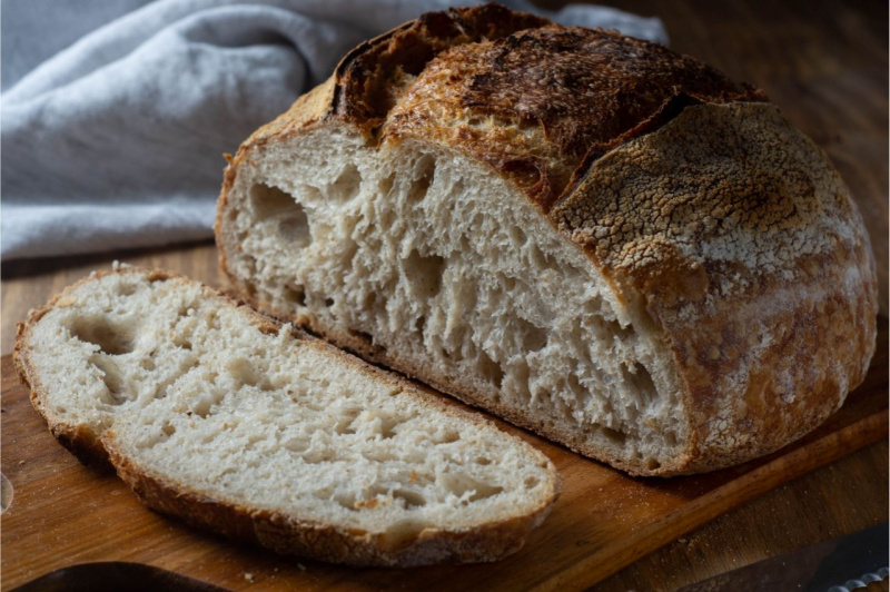 fetta di pane a lievitazione naturale croccante su tagliere di legno strofinaccio