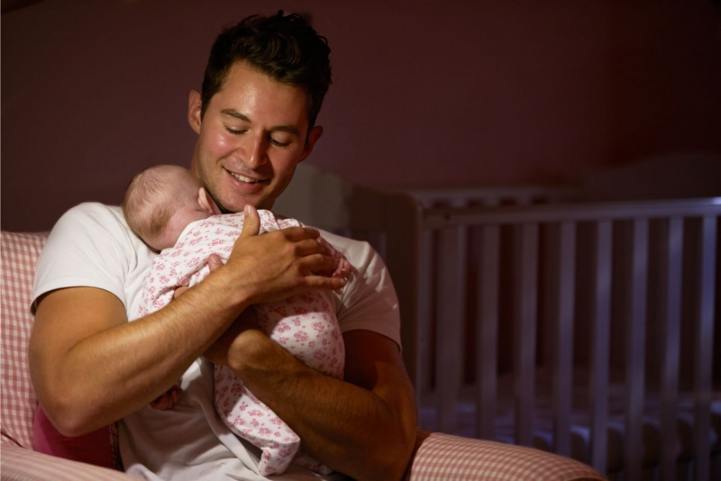 uomo tiene tra le braccia figlio neonato coccole conforto culla