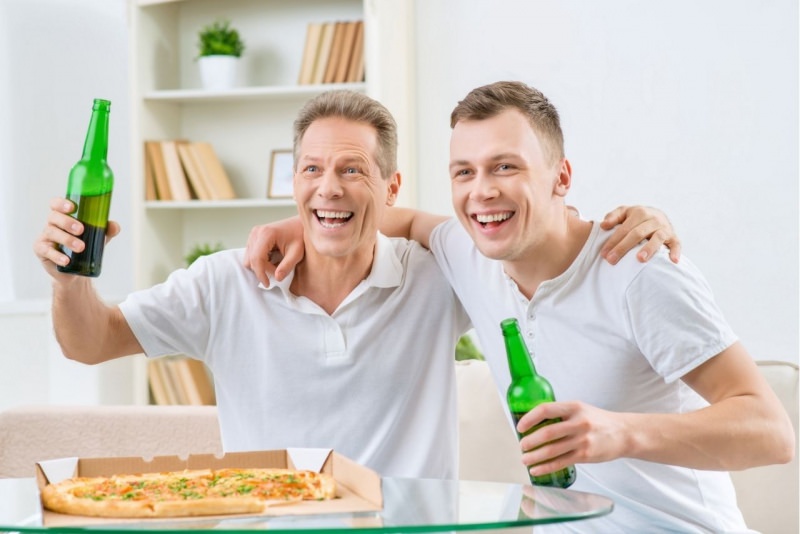 pap e figlio adulto bevono birra preferita mangiando pizza a casa