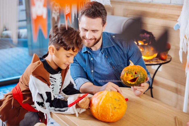 pap e figlio dipingono intagliano zucche halloween in casa