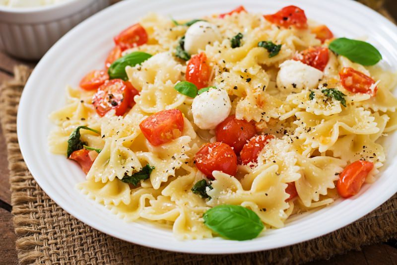 insalata di pasta farfalle fette di pomodoro rosso mozzarella fiordilatte foglie di basilico primo piatto pronto fresco