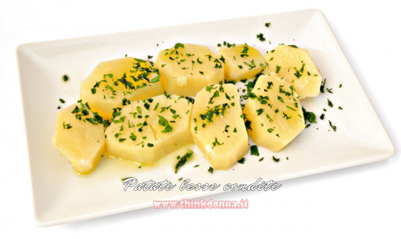 Fette di patate lesse condite con olio extravergine d'oliva e prezzemolo su piatto rettangolare