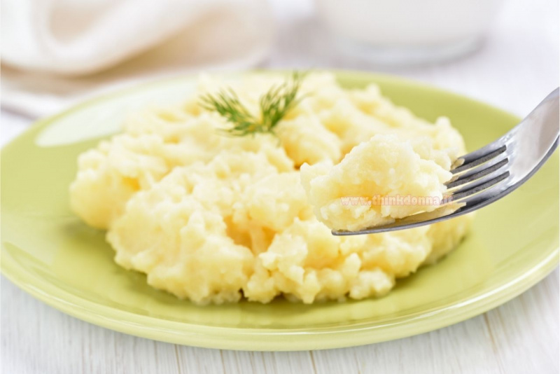 piatto con patate schiacciate con forchetta su tavolo legno grigio