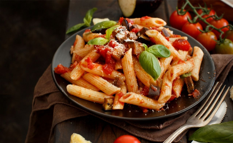 piatto di pasta italiana penne rigate melanzane basilico pomodori cucina siciliana
