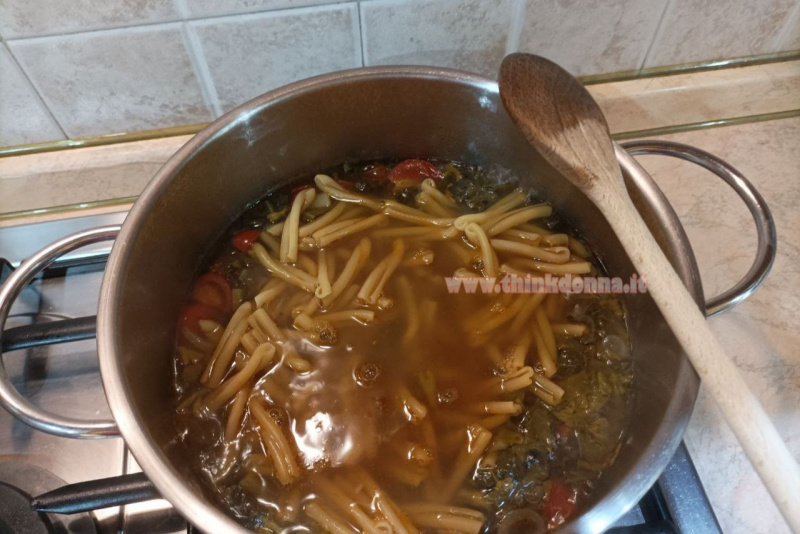 preparazione cottura pasta caserecce con i tinnirumi tenerumi taddi pomodorini pentola acciaio cucchiaio di legno su piano cottura