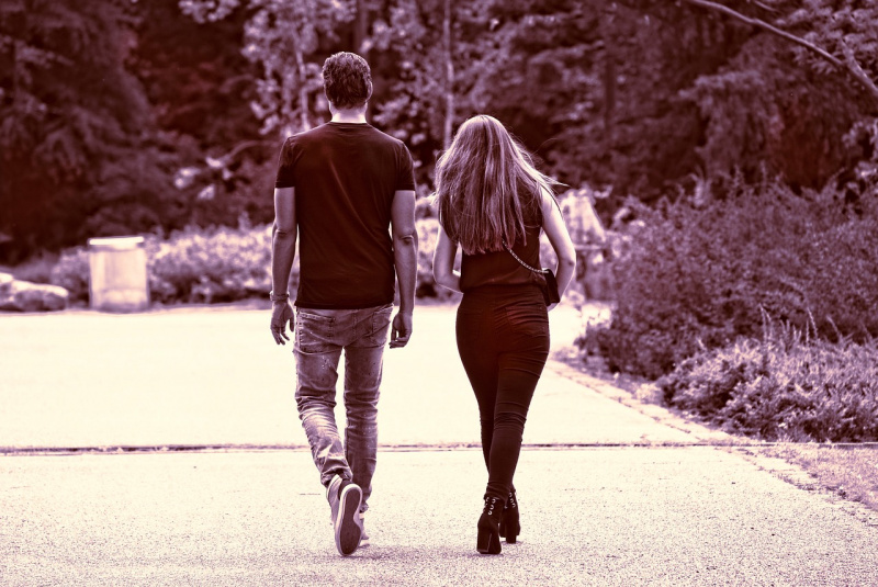 coppia uomo e donna di spalle camminano vicini lungo viale