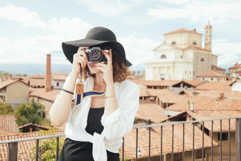 turismo donna cappello nero fotografa Viaggiare ad aprile, dove andare? Le migliori mete di viaggio per il Ponte di Pasqua.