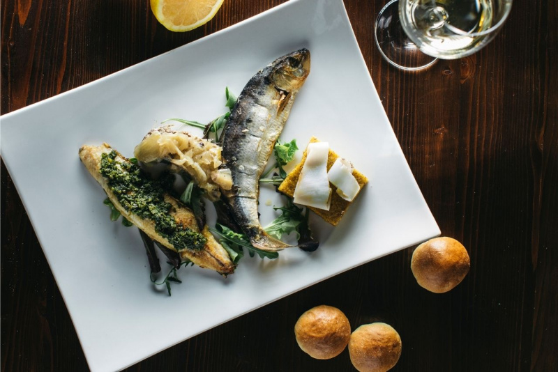 piatto pronto di pesce misultin polenta tarassaco limone tavola bicchiere di vino