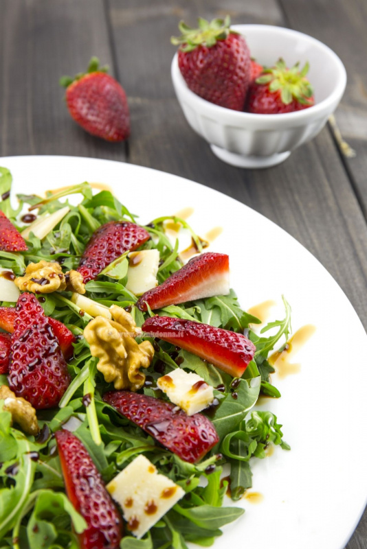 contorno insalata rucola fragola grana padano aceto balsamico gherigli noci ciotola ceramica bianca fragola su tavolo legno