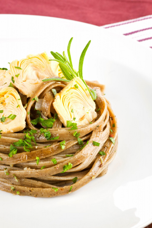 ricetta tagliatelle integrali cuori di carciofi prezzemolo su piatto bianco