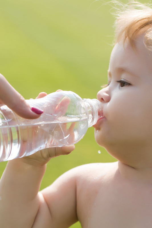 mano della mamma donna fa bere bambino piccolo acqua dalla bottiglia