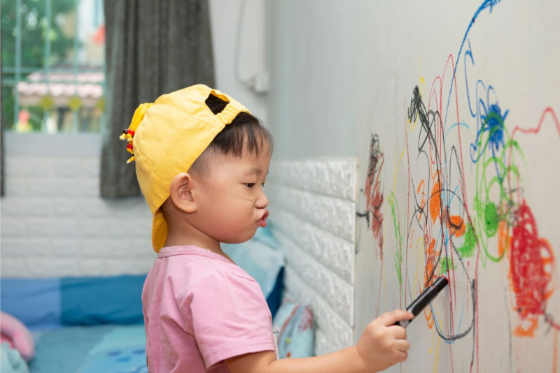 scarabocchi sul muro bambino si diverte a scrivere sul muro parete