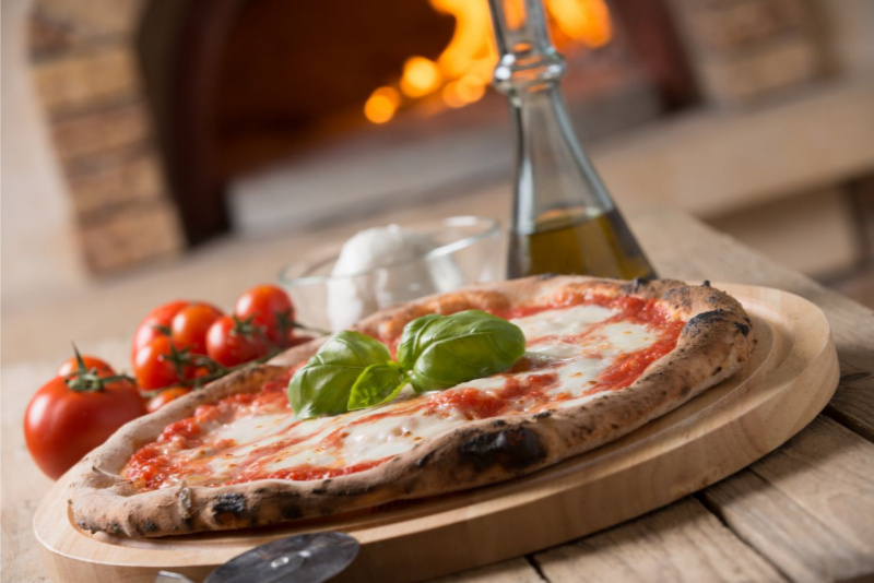 pizza margherita pronta su tagliere legno 