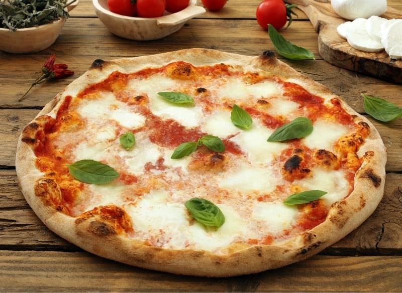 pizza margherita pomodoro basilico mozzarella su piano legno ciotole peperoncino