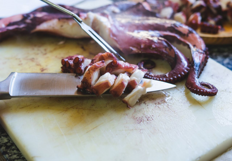 preparazione insalata polpo lesso tagliato su tagliere forchettone coltello