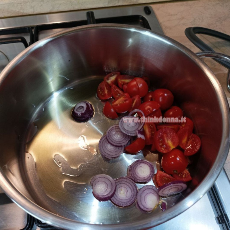 cipolla a fette pomodorini tagliati dentro pentola con olio evo su fornello
